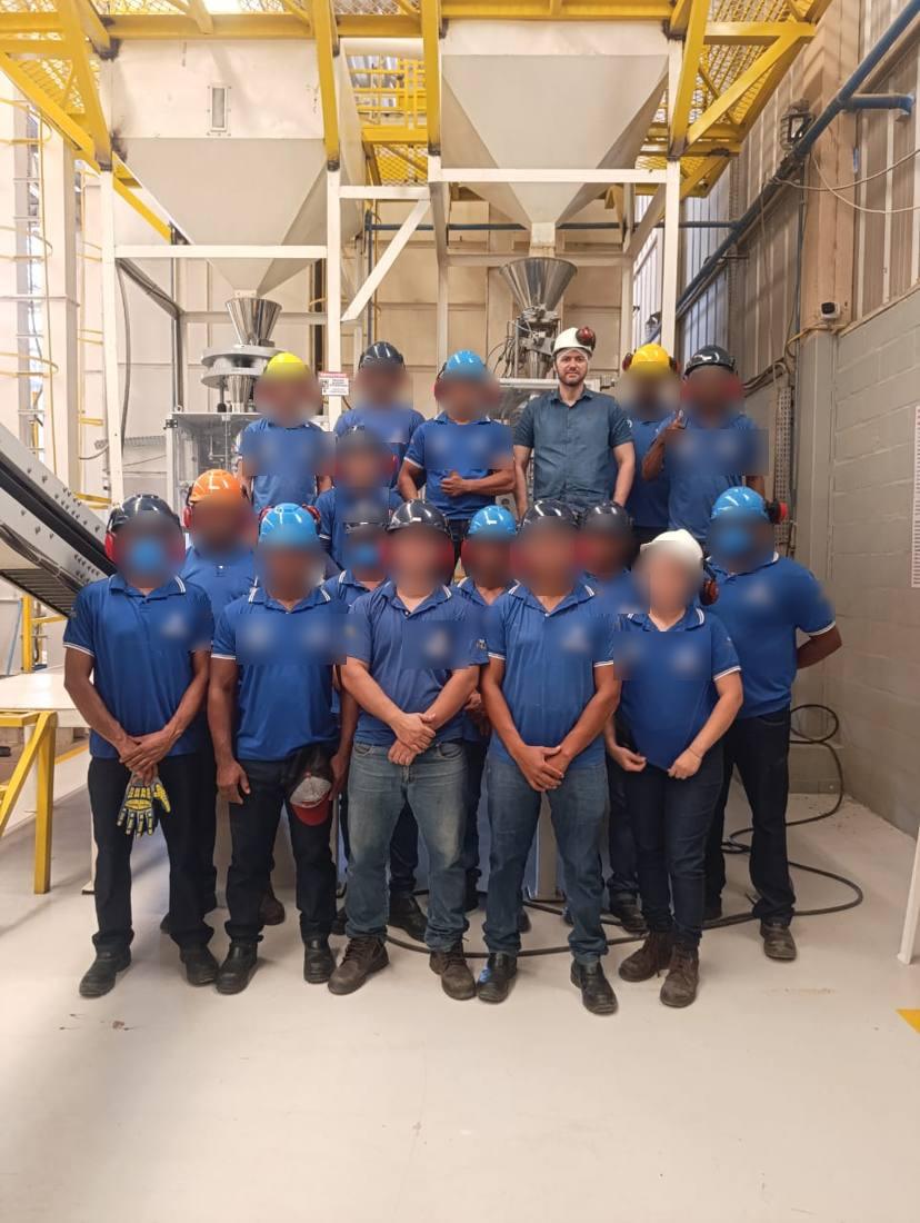 Turma de operadores reunida em frente à linha de empacotamento após o treinamento